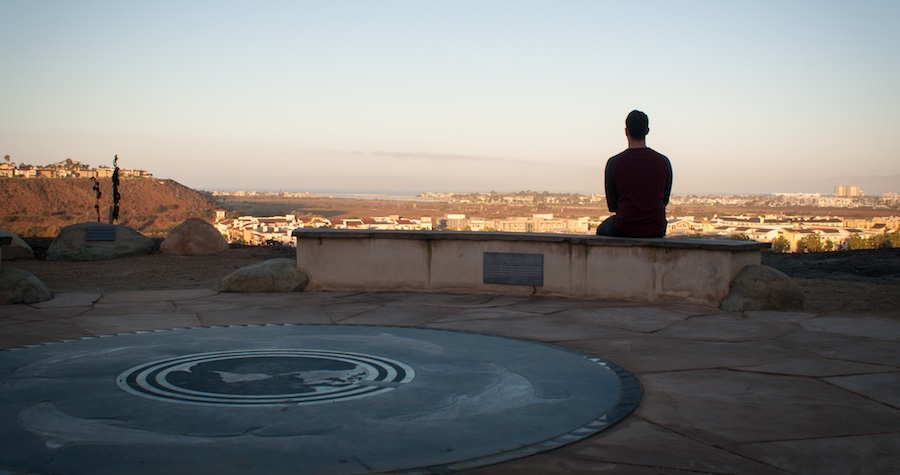 Male student sitting at the memorial back toward the camera